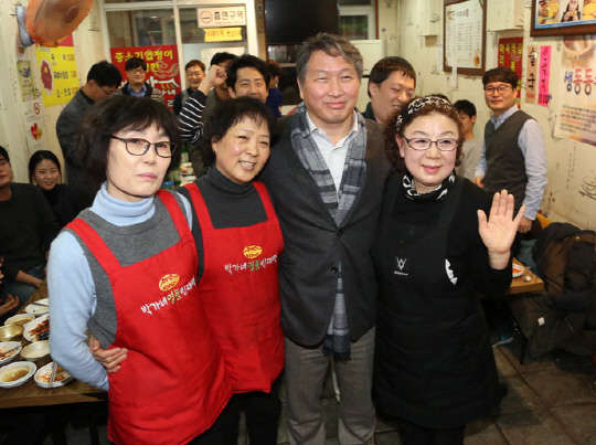 최태원 SK그룹 회장(왼쪽 세번째)이 지난 23일 서울 광장시장의 한 가게를 깜짝 방문해 상인들의 인증샷 요청에 포즈를 취하고 있다.  SK그룹 제공